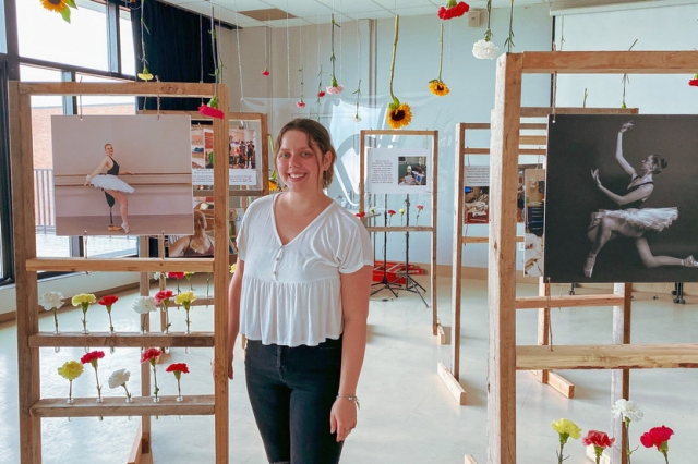 student photographer posing with photos of a ballerina with an artificial leg.