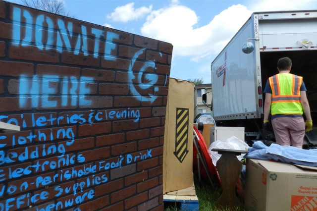 person wearing a safety vest loading donated items into a moving truck.