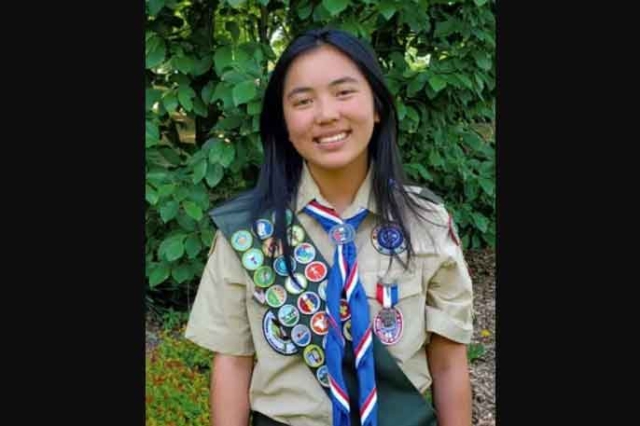 student wearing a Boy Scout uniform with a sash and badges.