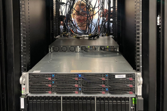 student looking through a space in a server rack.