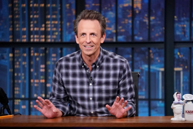 late night host Seth Meyers sitting at his desk.