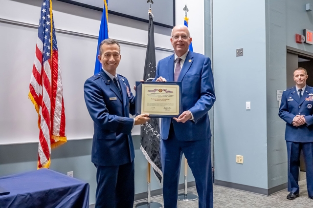 Air Force office and RIT president holding a certificate and posing for a photo.