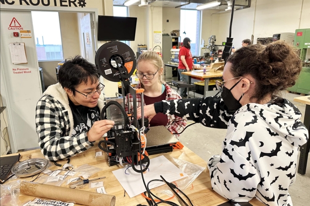 three college student assembling a 3D printer.