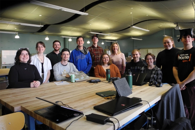 team of college students and professor sitting around a table.