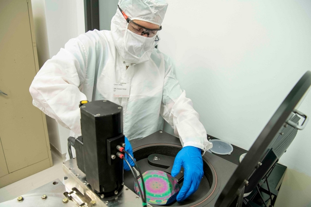 person wearing clean suit handling a semiconductor.