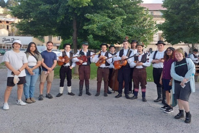 college students standing next to traditional Croatian folklore musicians.