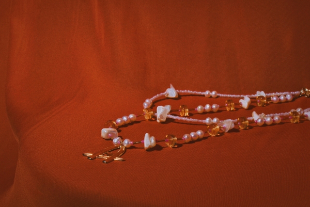 A beaded gemstone necklace set against a red background.