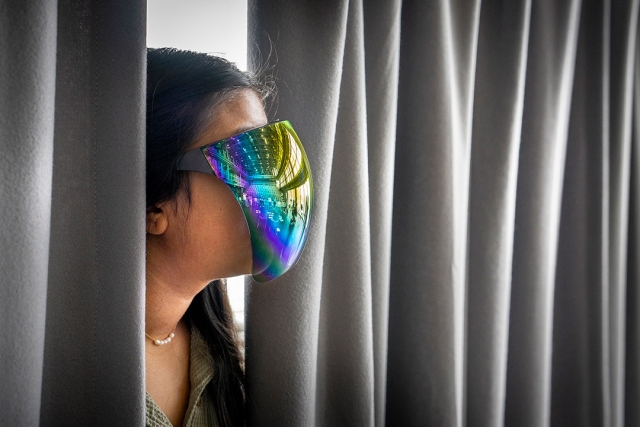 a person is show peeking out from curtains wearing a reflective face mask as a part of the show.
