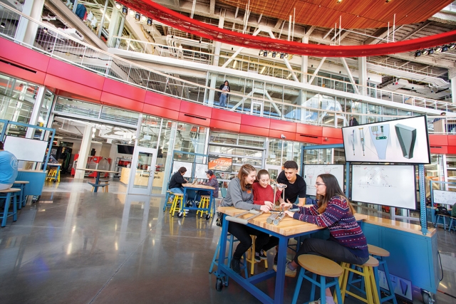 four students sit at a table testing a small product in one of the SHEDs makerspaces.