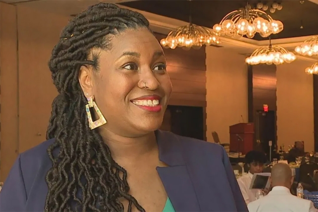 Katrina Overby is shown in a banquet hall speaking to a member of the media.