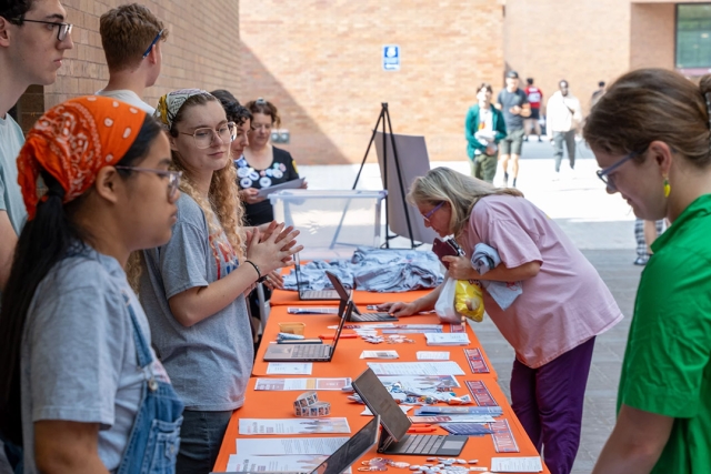 several students stand in front of and behind a table displaying information about voter registration on the R I T campus.
