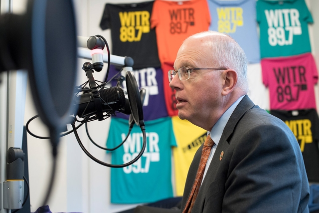 David Munson appears in a radio studio with W I T R shirts behind him.