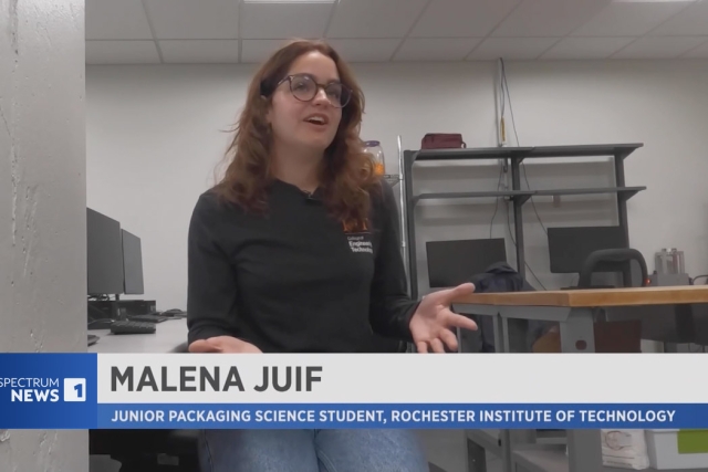 a student appears on spectrum news wearing a black long sleeve shirt in a packaging studio.