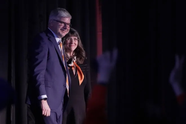 William Sanders appears next to his wife, Emily, on a stage at RIT.