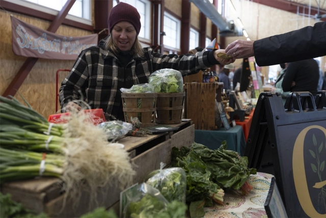 A femal employee of handles a purchase and hands over cash to a customer at the Brighton Farmers Market.