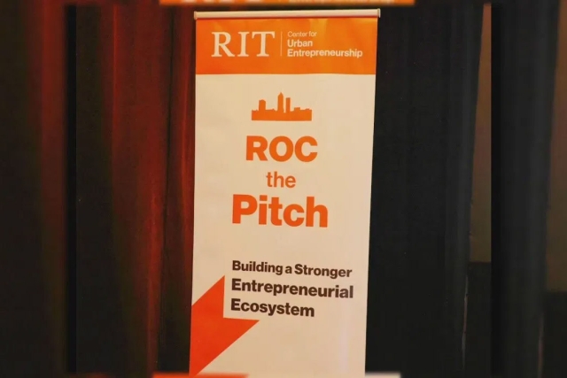 a poster for Roc the Pitch stands on a stage