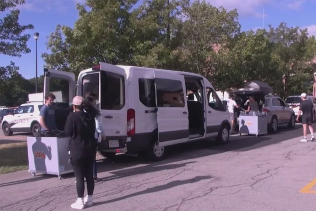 students unload a white van during R I T move in day.