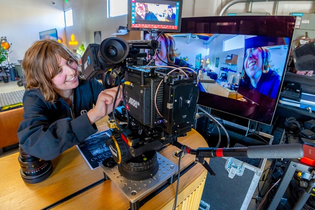 a woman uses a video camera that is sitting on a desk