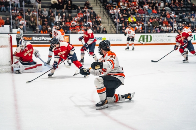 players on the R I T mens hockey team skate on the ice near the goal.