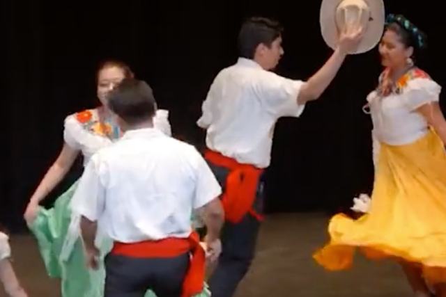 dancers in western wear move across a stage.