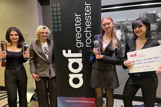 A group of students pose with hardware and a large check.