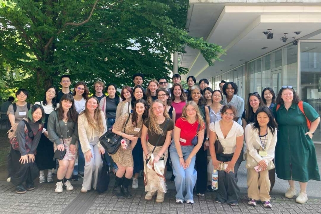 A group of students posing outside in front of a building with trees in the background