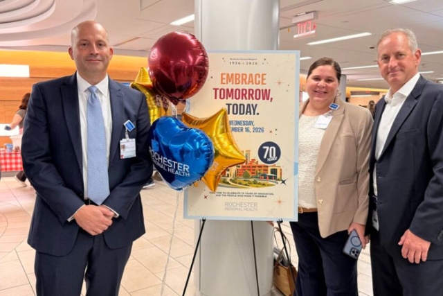 three people stand next to a sign with balloons celebrating the anniversary of R G H