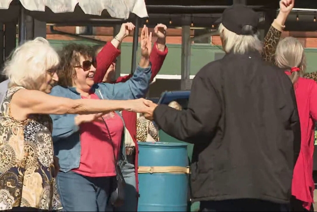 people celebrate italian heritage at the rochester public market by dancing in a circle.