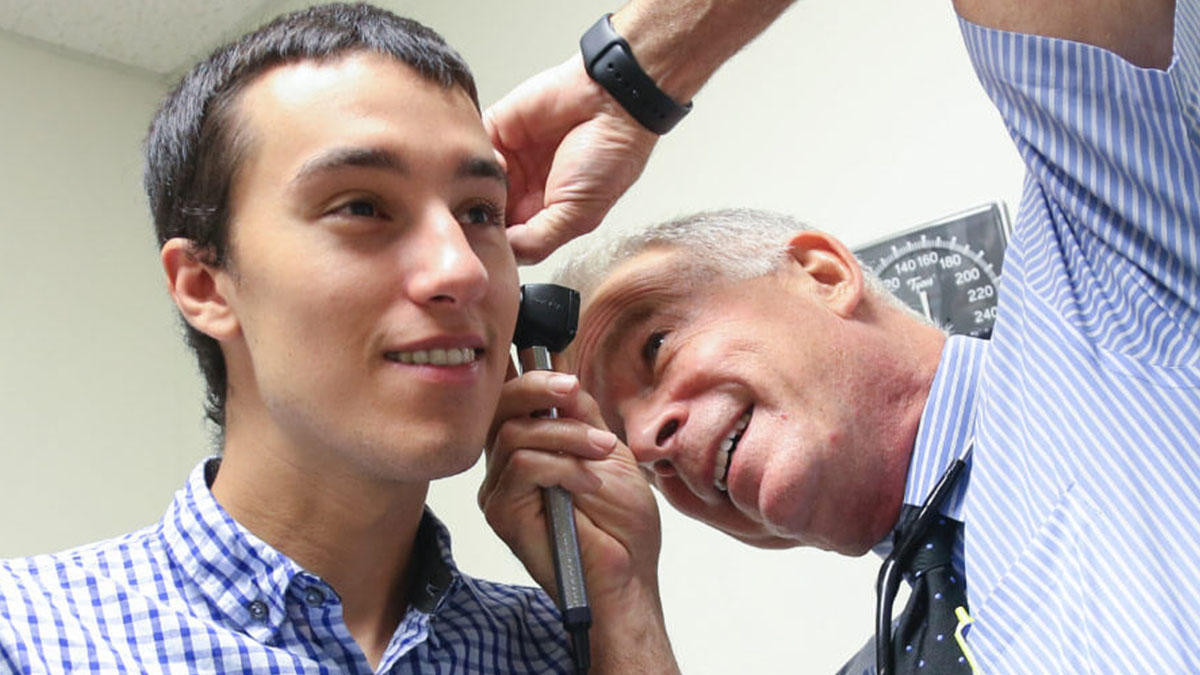 A medical professional examining inside a patient's ear.