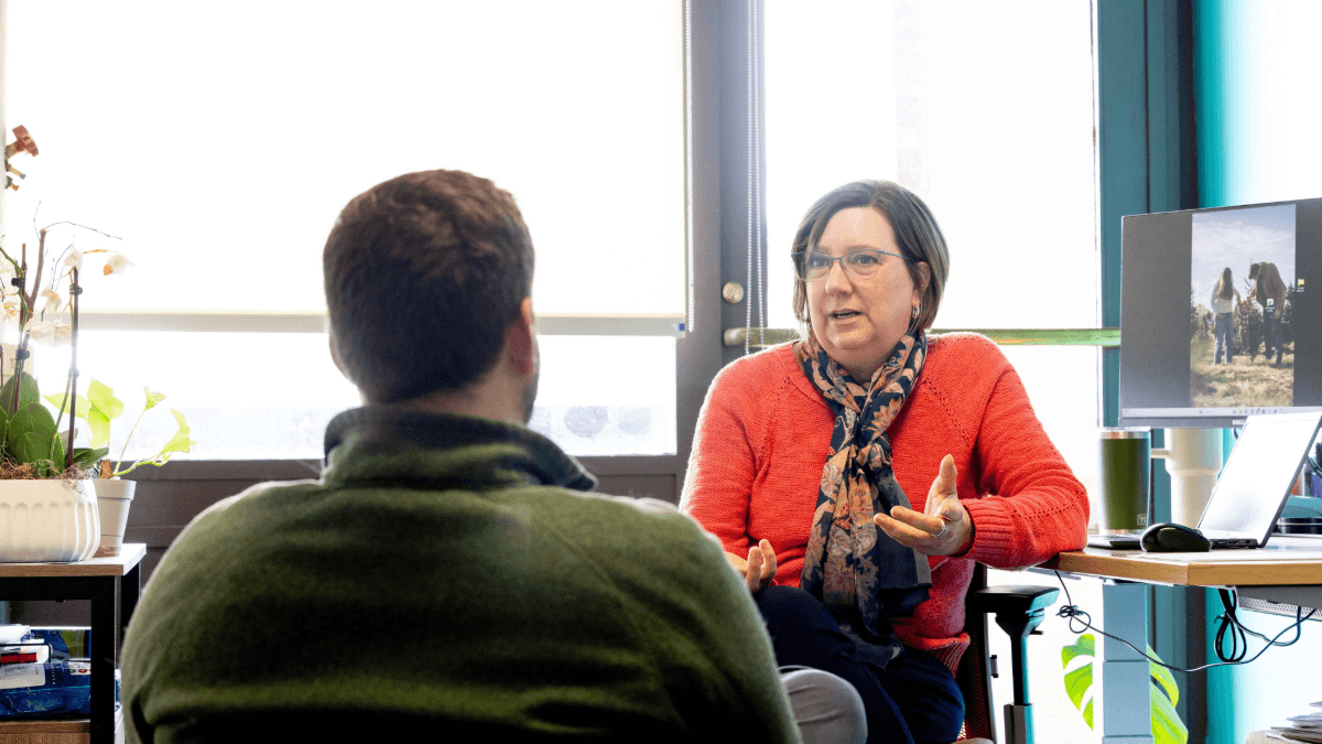 A student speaks with a staff member at the RIT Student Conduct and Conflict Resolution office while another staff member works at a desk in the background