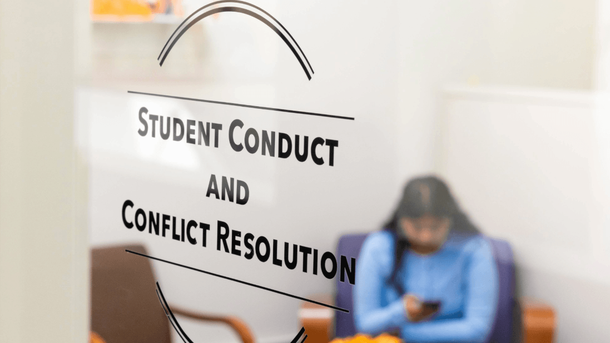 A student sitting in a waiting room at the student conduct and conflict resolution office at RIT looking at their phone
