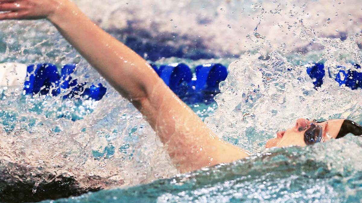 student swimming the backstroke in a pool lane.