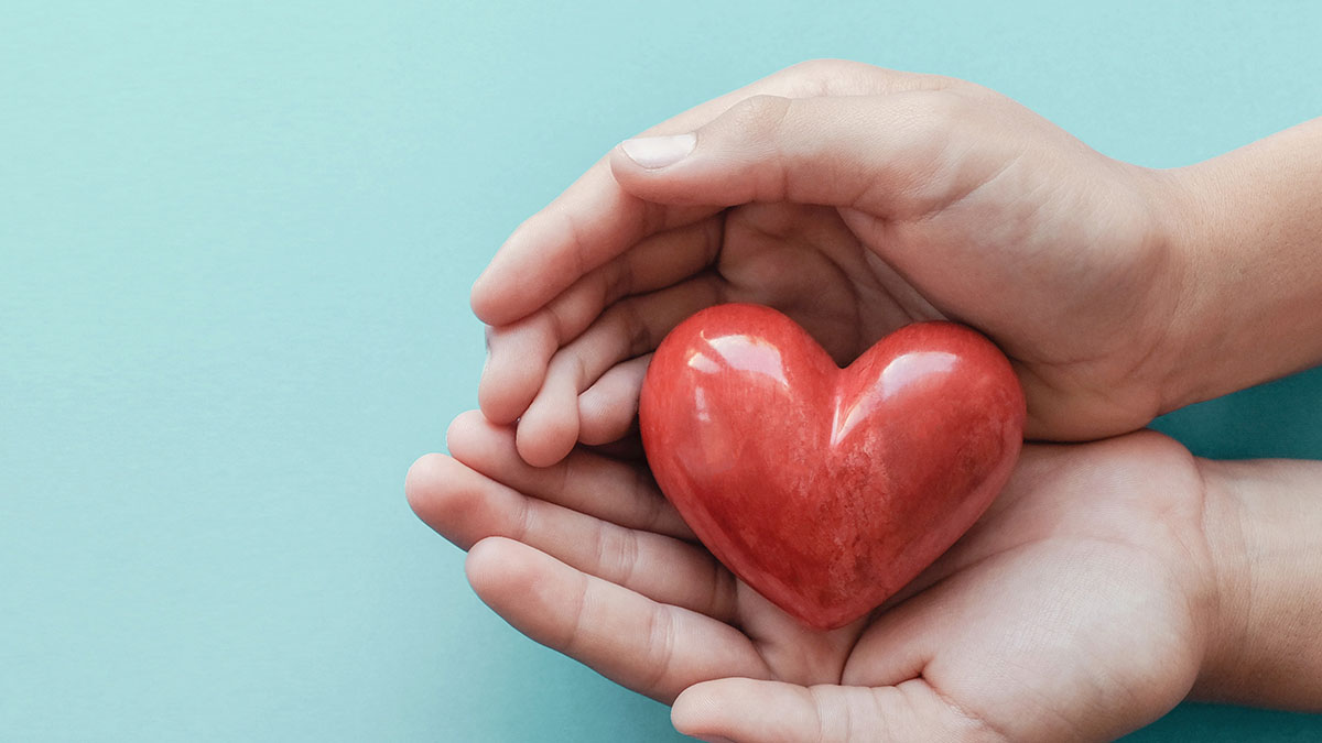 A pair of hands holding a ceramic heart.