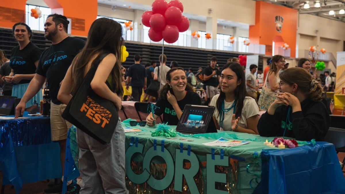 Students tableing at Tiger Activities Fair explaining to a student about their club