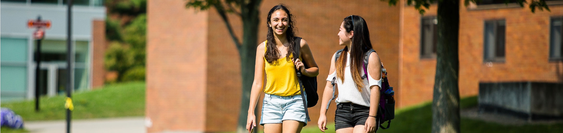 Two R I T students walking outside of a residence hall. 