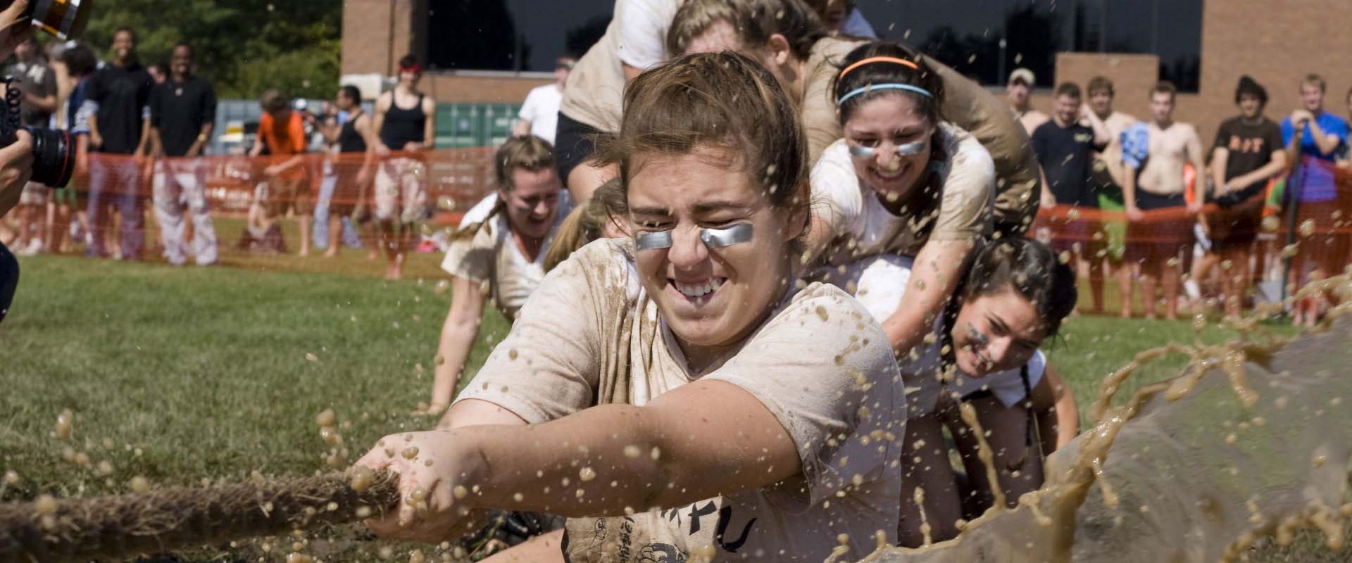 A team being pulled into the mud at a tug of war event.