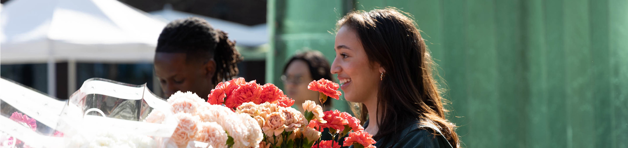 A student smiles while looking onto buckets of carnations at the CAB Tea Party event
