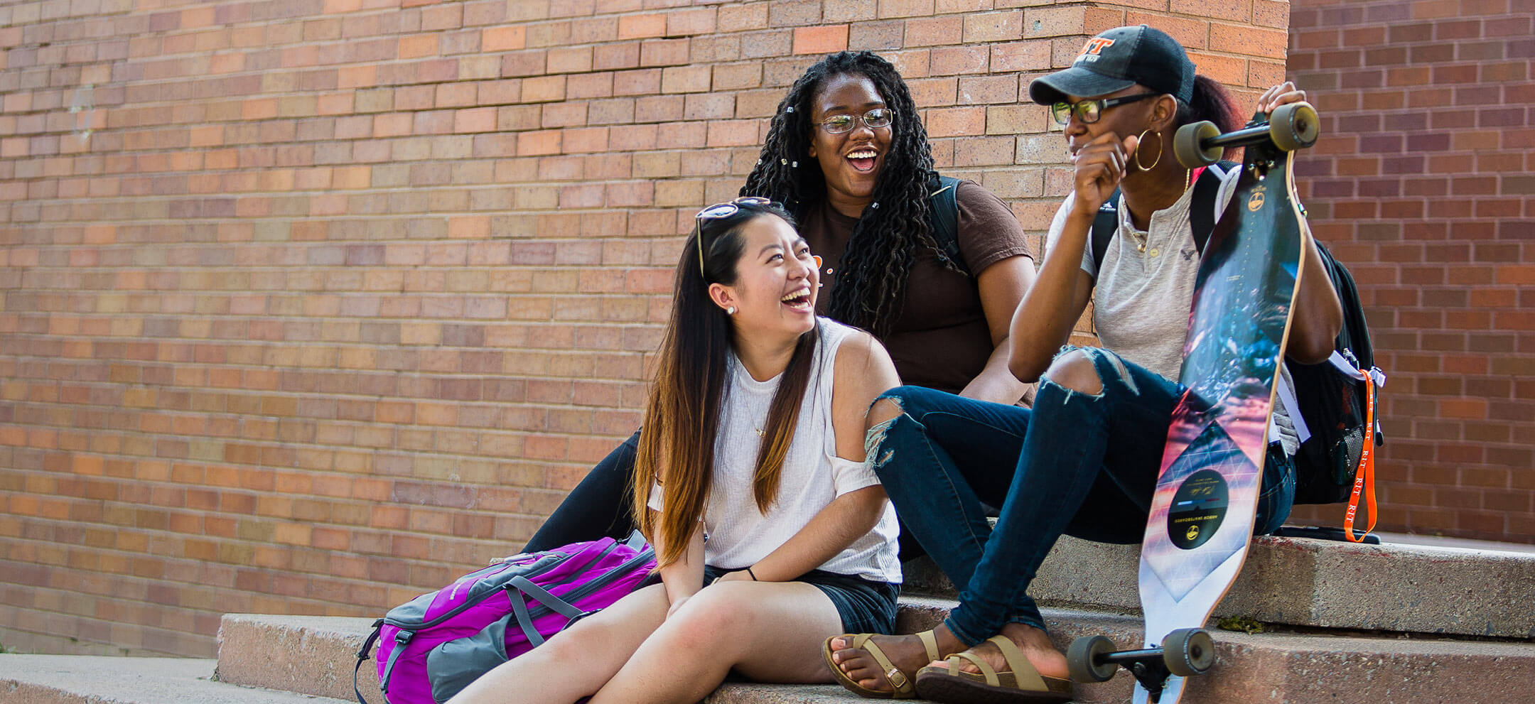Three female students laughing while sitting on steps