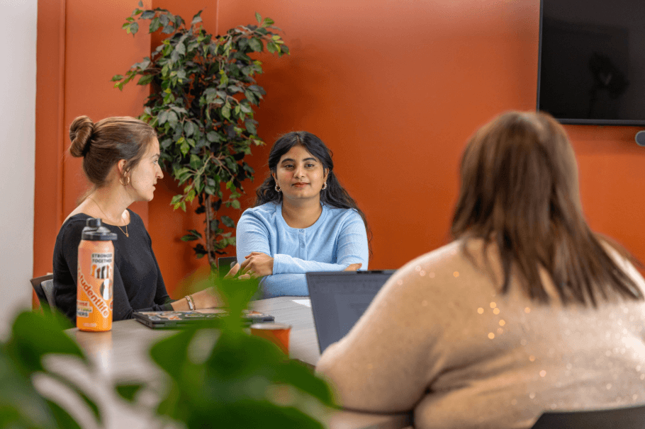A student and staff members sitting at a table with a computer having a calm discussion
