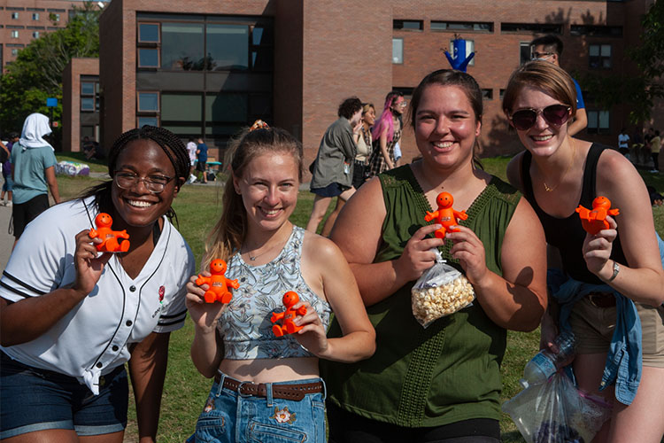 Students pose smiling while holding orange stress squeeze toys