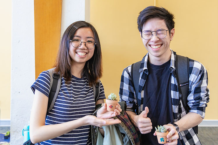 Two students laugh while posing with succulents