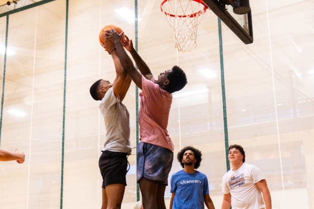 Two students play basketball while two others watch at the Intramural Free Agent night.