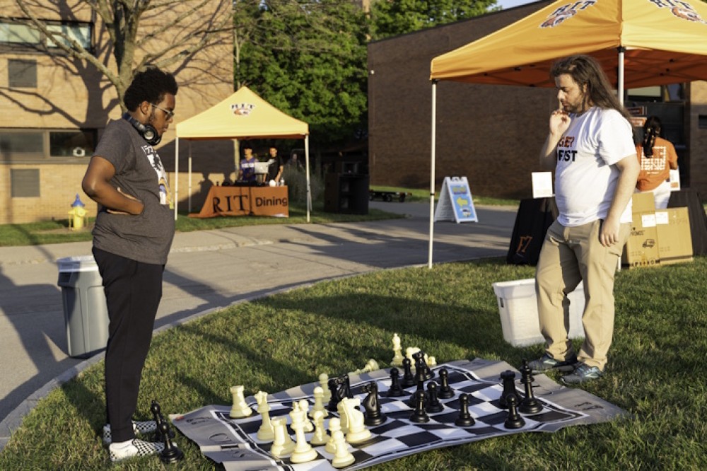 Two students play enlarged chess on the grass at the Lawn Bash.