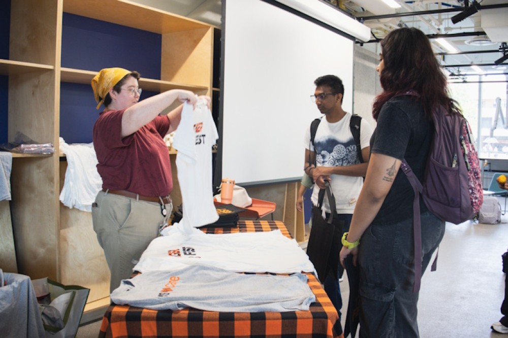  Two students are handed a white shirt that says Tiger Fest on it.