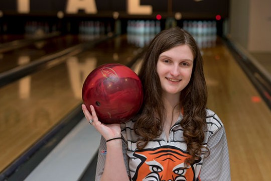 Laura Branch holding a bowling ball in front of bowling lanes