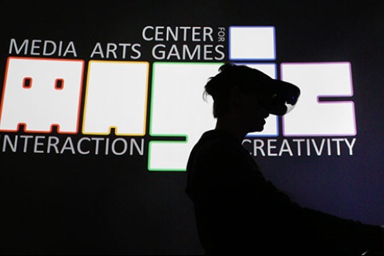 Student with VR headset, in front of the MAGIC logo.
