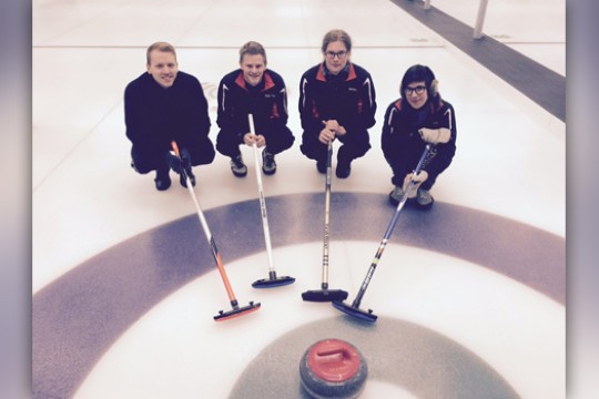 People posing near a curling puck