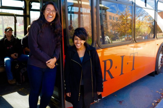 Two people posing next to bus