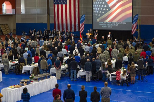 Group of people gathered in front of American Flag for Veteran's ceremony.
