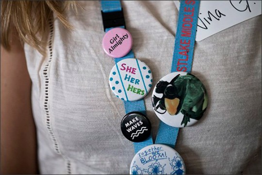 Lanyard with buttons that read "Girl Almighty," "She, Her, Hers," and "Make Waves."
